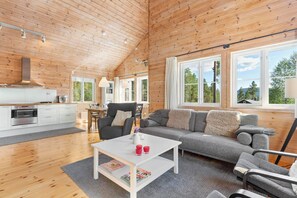 A spacious living area with a wooden ceiling, a sofa, a coffee table, and a kitchen area with a stove and cabinets. - Chalet Vrådal 8p - Three Bedroom Chalet, Sleeps 8 (Vrådal)