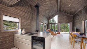 Une cuisine moderne dotée d’un grand îlot central, d’un four encastré et d’un coin repas avec des chaises et une table en bois.