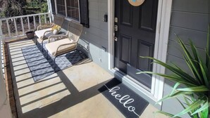 A porch with two wicker chairs, a small table, and a welcome mat. - Charming 3-bedroom house ready for the Masters (Martinez)