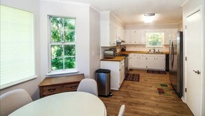 A compact kitchen with white cabinets, a refrigerator, and a window providing a view of greenery. - Charming 3-bedroom house ready for the Masters (Martinez)