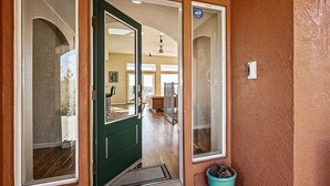 A green door with a glass panel, a potted plant, and a number plaque on the wall. - House in Bedford Woods (Placerville)