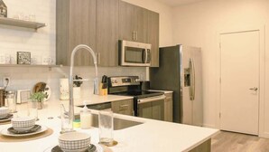 A modern kitchen with a central island, stainless steel appliances, and a minimalist design. - Downtown Retreat w/ Pool, Hot Tub & Fire Pit (Louisville)