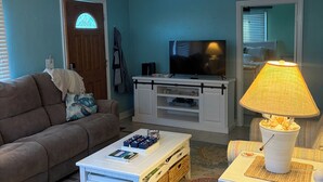 Ett vardagsrum med en soffa, ett soffbord, en tv, en takfläkt och en lampa.