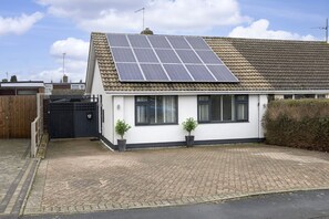 Ein Wohnhaus mit Ziegeldach, Solaranlage, gepflasterter Auffahrt und schwarzem Tor.