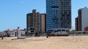 Ein Strand mit einem hohen Gebäude im Hintergrund.