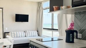 Eine moderne Küche mit Einbauofen, Wasserkocher und flachbildfernseher an der Wand.