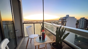 Ein Balkon mit Tisch, Stühlen und Pflanzen in Töpfen.