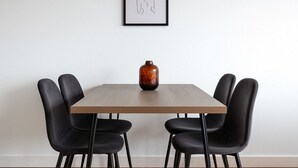 A dining table with four black chairs, a wooden table, and a vase on the table. - Luxury Studios | E8 4DN | Balcony (London)