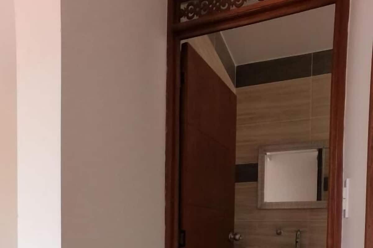 A narrow hallway leading to a kitchen with wooden cabinets and a tiled backsplash.