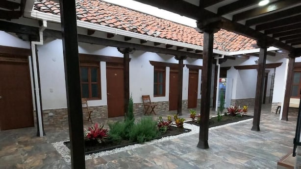 A covered courtyard with stone flooring, wooden pillars, and a tiled roof. - HOTEL COLONIAL A 100 MTS DE LA BASILICA (Guadalajara de Buga)