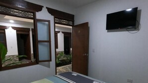 A room with a bed, a TV mounted on the wall, and a door leading to another room. - HOTEL COLONIAL A 100 MTS DE LA BASILICA (Guadalajara de Buga)