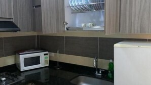 A kitchen with wooden cabinets, a microwave, a sink, and a dish rack with plates. - HOTEL COLONIAL A 100 MTS DE LA BASILICA (Guadalajara de Buga)