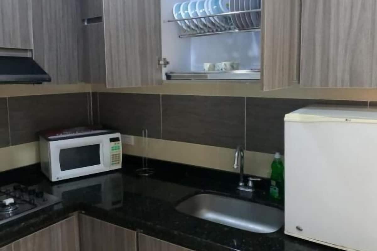A kitchen with wooden cabinets, a microwave, a sink, and a dish rack with plates.