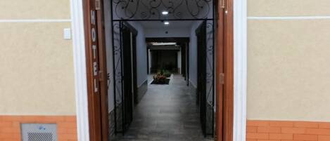 Entrada de hotel con un cartel con número sobre la puerta, suelo de baldosas y pared de ladrillo.