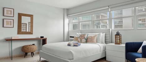 A bedroom with a bed, bedside tables, a lamp, a window, and a wall-mounted shelf.
