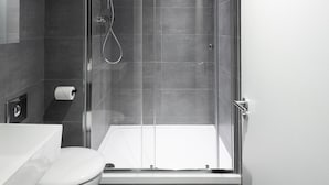 Un baño moderno con ducha de vidrio, inodoro y lavamanos.