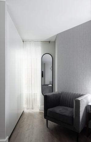 Une pièce moderne avec un canapé gris, un grand miroir et un plancher en bois.