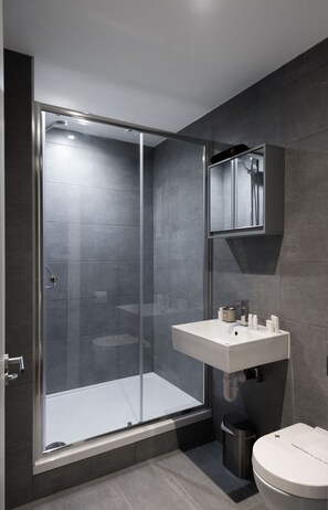 A modern bathroom with a glass-enclosed shower, a white sink, and a toilet. - Studio near Oxford Street (London)