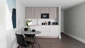 A modern kitchen with a microwave, coffee maker, and a small dining area with a table and chairs. - Studio near Oxford Street (London)