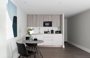 A modern kitchen with a microwave, coffee maker, and a small dining area with a table and chairs. - Studio near Oxford Street (London)