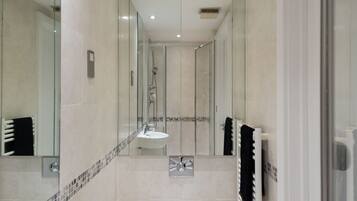 A modern bathroom with a large mirror, a sink, a toilet, and a shower area.