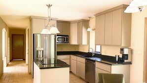 A modern kitchen with stainless steel appliances, a black countertop, and light-colored cabinetry.