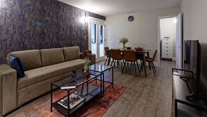 Een woonkamer met een bank, salontafel en een eethoek met stoelen en een tafel.