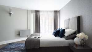 Een moderne slaapkamer met een bed, nachtkastje en een raam met gordijnen.