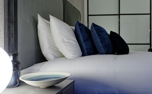 A neatly made bed with white and dark blue pillows, a bowl on a bedside table, and a modern room design. - Two-Bedroom Apartment near Oxford Street (London)