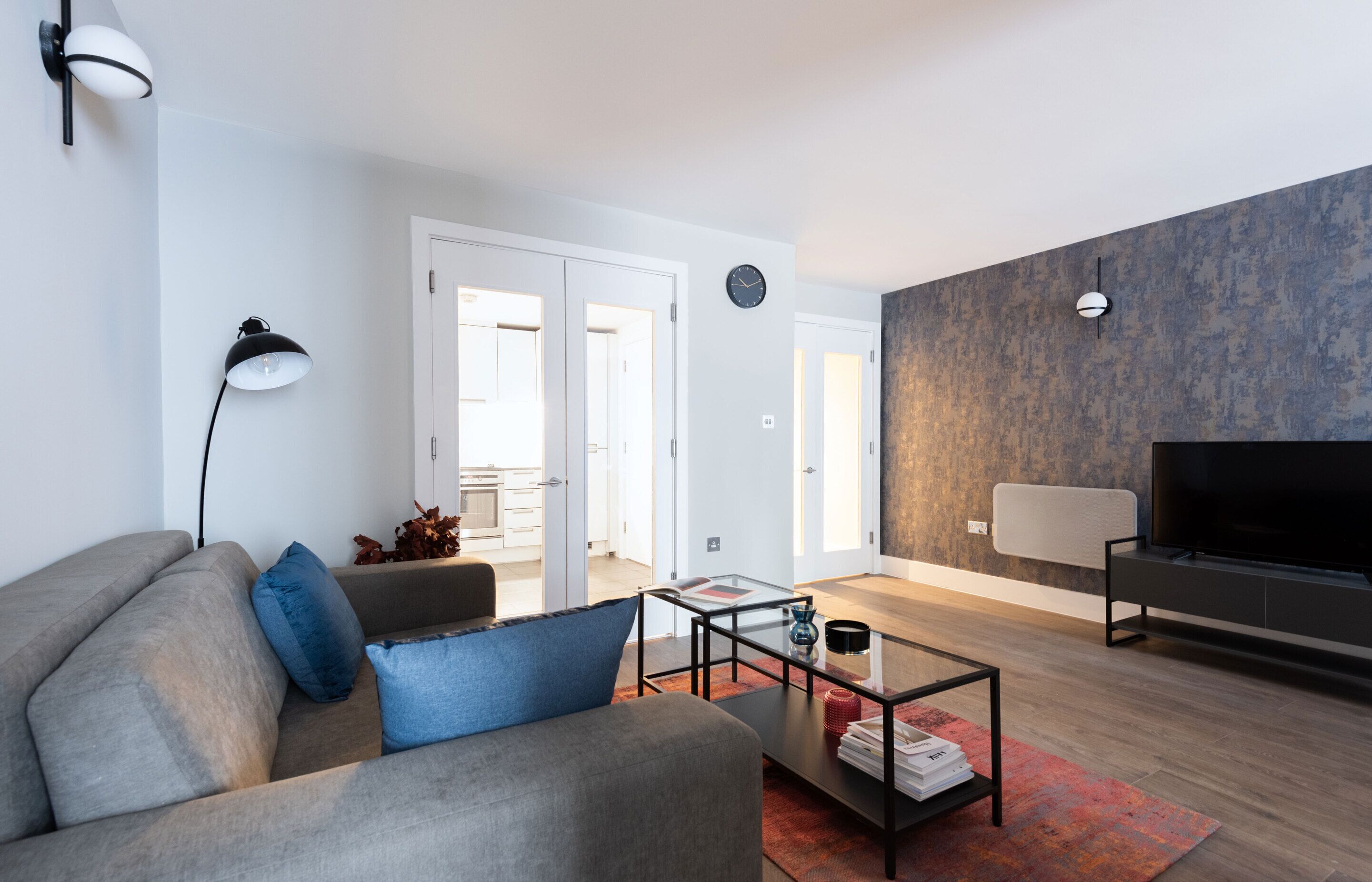 A modern living room with a sofa, coffee table, and a flat-screen TV.