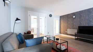 A modern living room with a sofa, coffee table, and a flat-screen TV.