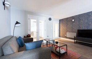 A modern living room with a sofa, coffee table, and a flat-screen TV. - Two-Bedroom Apartment near Oxford Street (London)