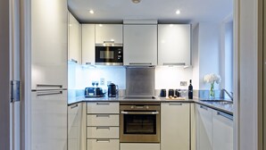 Een moderne keuken met roestvrijstalen apparatuur, witte kastjes en een betegelde spatwand.