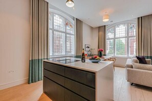 Eine moderne Küche mit Kochinsel, großen Fenstern und einer Essecke inklusive Sofa.