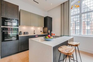 Une cuisine moderne dotée d’appareils électroménagers intégrés, d’un îlot central et de tabourets de bar.