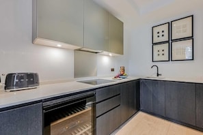 Een moderne keuken met een inbouwvaatwasser, een broodrooster en een wijnkoeler.