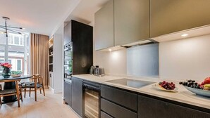 Een moderne keuken met donkere kastjes, een ingebouwde oven en een groot kookeiland met spoelbak.
