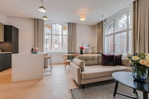 A modern living room with a sofa, a dining table, and a kitchen area. - Three-Bedroom Terrace Apartment (London)