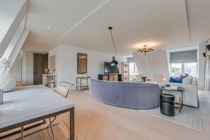 Een moderne woonkamer met een gebogen bank, een eettafel en een televisie.