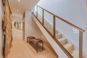 Een modern interieur met een trap, een bankje en een spiegel aan de muur.