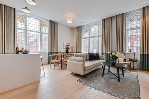Een ruime woonkamer met een bank, salontafel en eethoek.