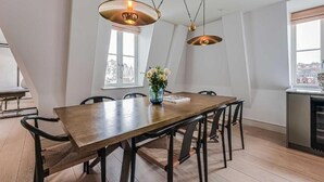 Un comedor con una mesa de madera, sillas negras e iluminación colgante.