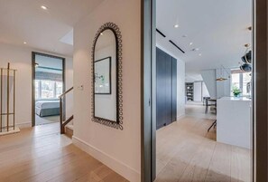 Un intérieur moderne avec un escalier, un grand miroir et un coin cuisine.