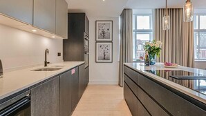 Une cuisine moderne dotée d’un îlot central, de luminaires suspendus et d’œuvres d’art encadrées accrochées au mur.