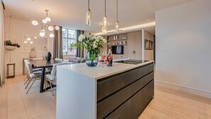 Une cuisine moderne dotée d’un îlot central, de luminaires suspendus et d’un coin repas avec un canapé.