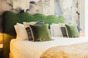 A bed with a green upholstered headboard, white and striped pillows, and a woven throw blanket. - Three-Bedroom Superior Apartment (London)