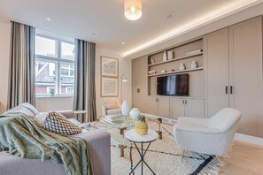 Un salon moderne comprenant un canapé, un fauteuil, une table basse et un téléviseur.