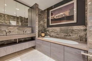 A modern bathroom with a large mirror, a bathtub, and marble walls. - Three-Bedroom Superior Apartment (London)