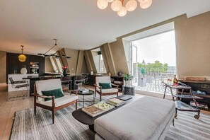 A modern hotel room with a large bed, two armchairs, a desk, and a balcony with a view. - Three-Bedroom Superior Apartment (London)