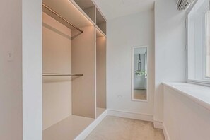 Un dressing accessible sans porte, doté d’un grand miroir et d’une fenêtre.